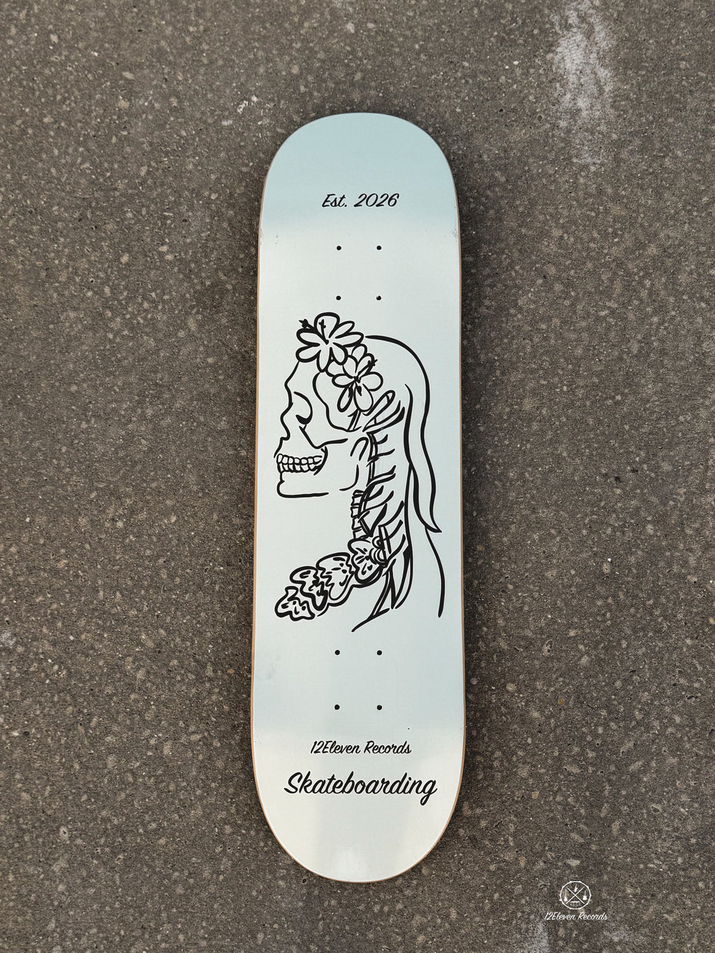 Skateboard deck with a skeleton design and 'Est. 2026' text on a gray background